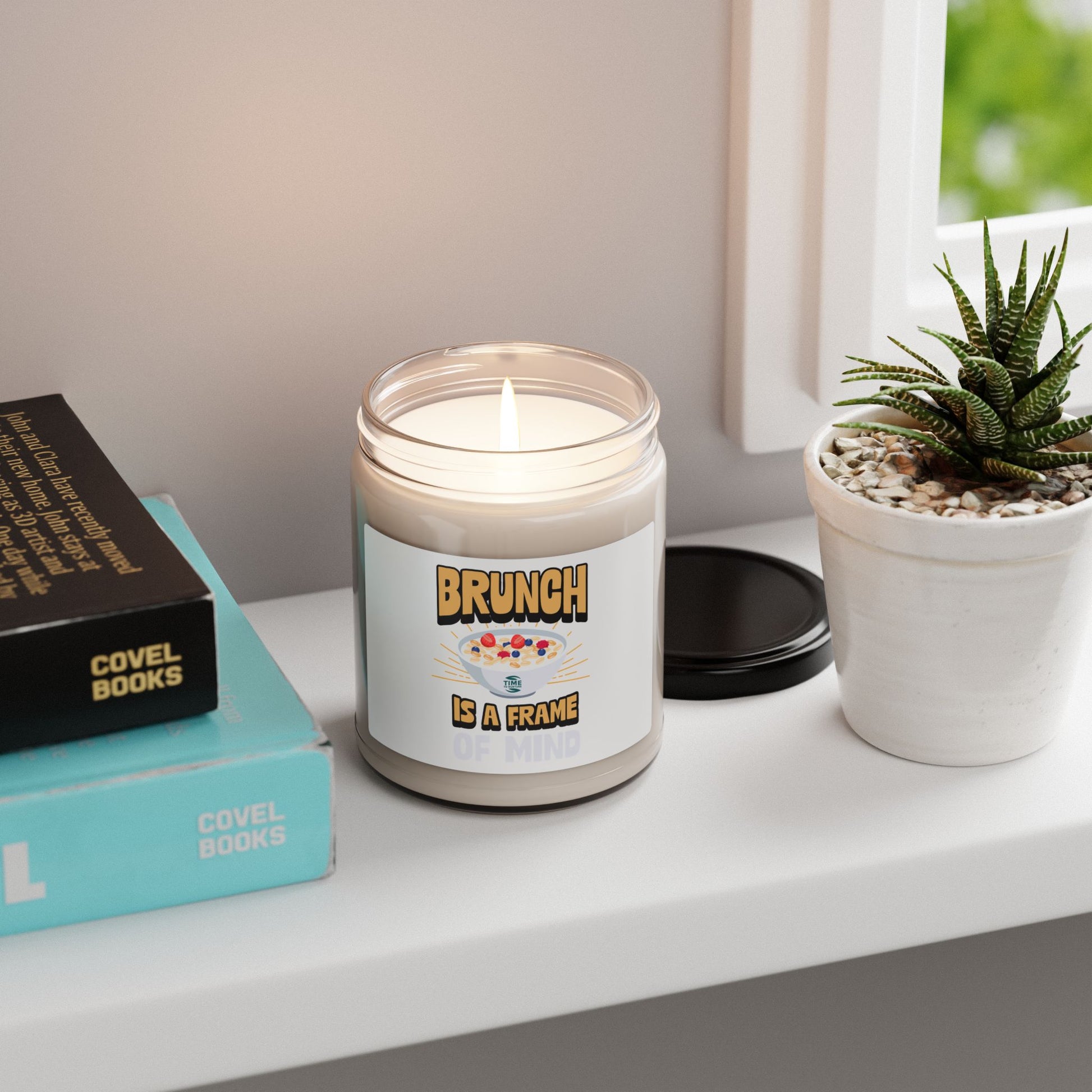 A "Brunch Is a Frame of Mind" scented soy candle in a stylish amber glass jar. The 9oz candle features natural soy wax, a cotton wick, and a long burn time, offering inviting aromatic scents for a cozy ambiance and relaxation.