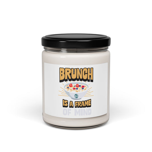 A "Brunch Is a Frame of Mind" scented soy candle in a stylish amber glass jar. The 9oz candle features natural soy wax, a cotton wick, and a long burn time, offering inviting aromatic scents for a cozy ambiance and relaxation.