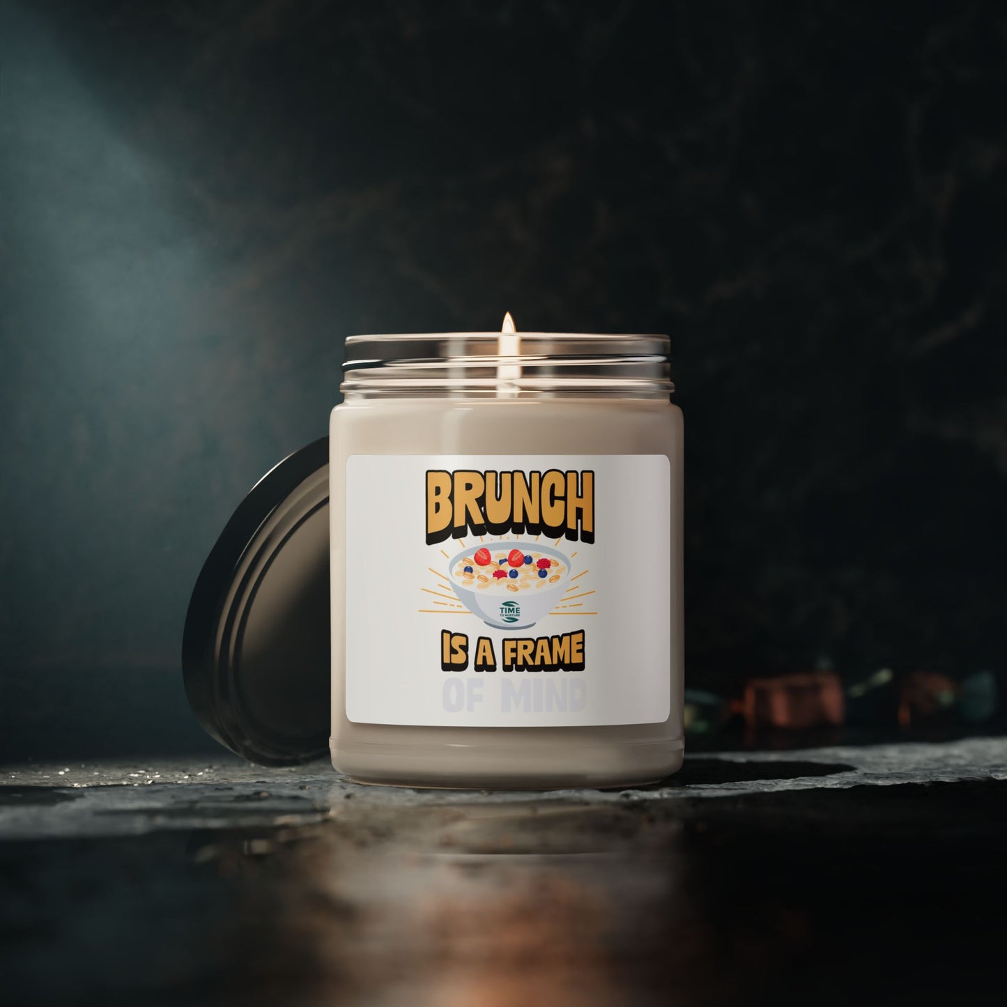 A "Brunch Is a Frame of Mind" scented soy candle in a stylish amber glass jar. The 9oz candle features natural soy wax, a cotton wick, and a long burn time, offering inviting aromatic scents for a cozy ambiance and relaxation.